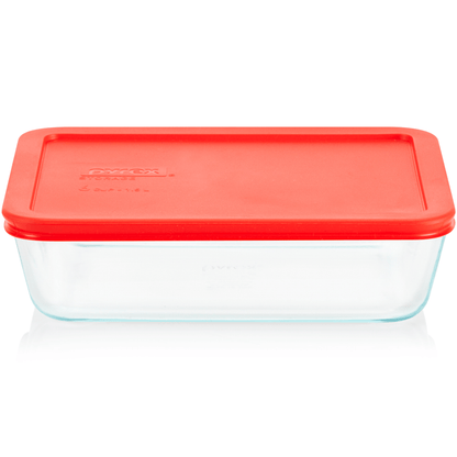 Clear glass food storage container with a red lid on a white background